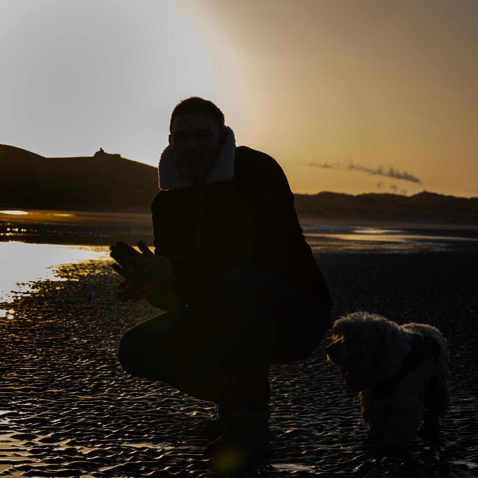 David crouching at sunset with dog